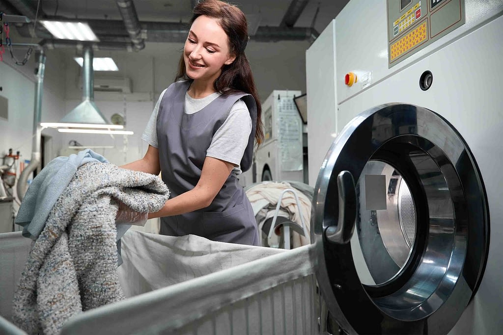 Laundry operator unloading an industrial washing machine