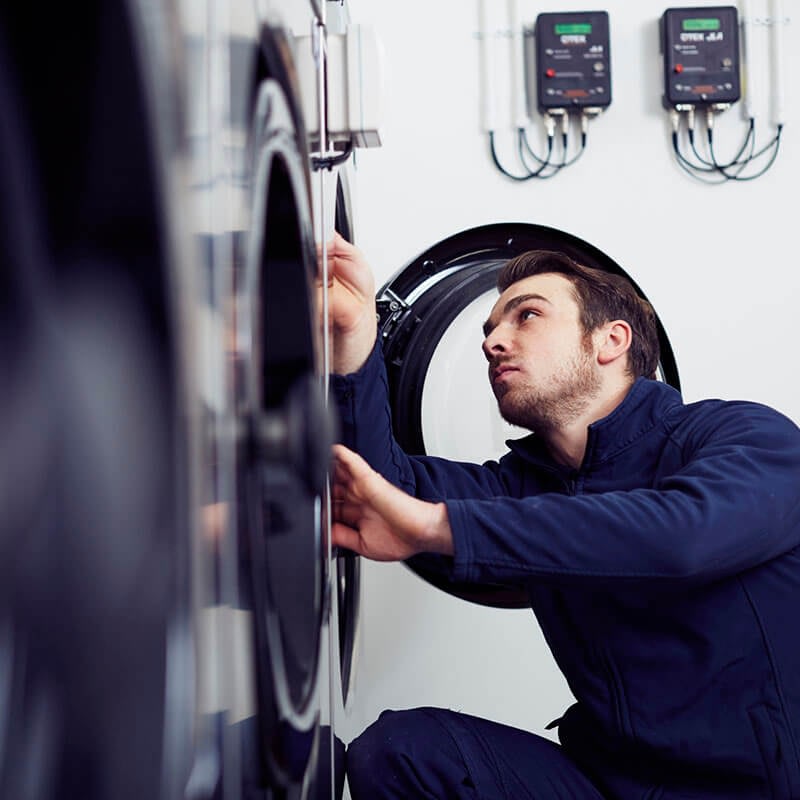 Engineer servicing commercial washing machine